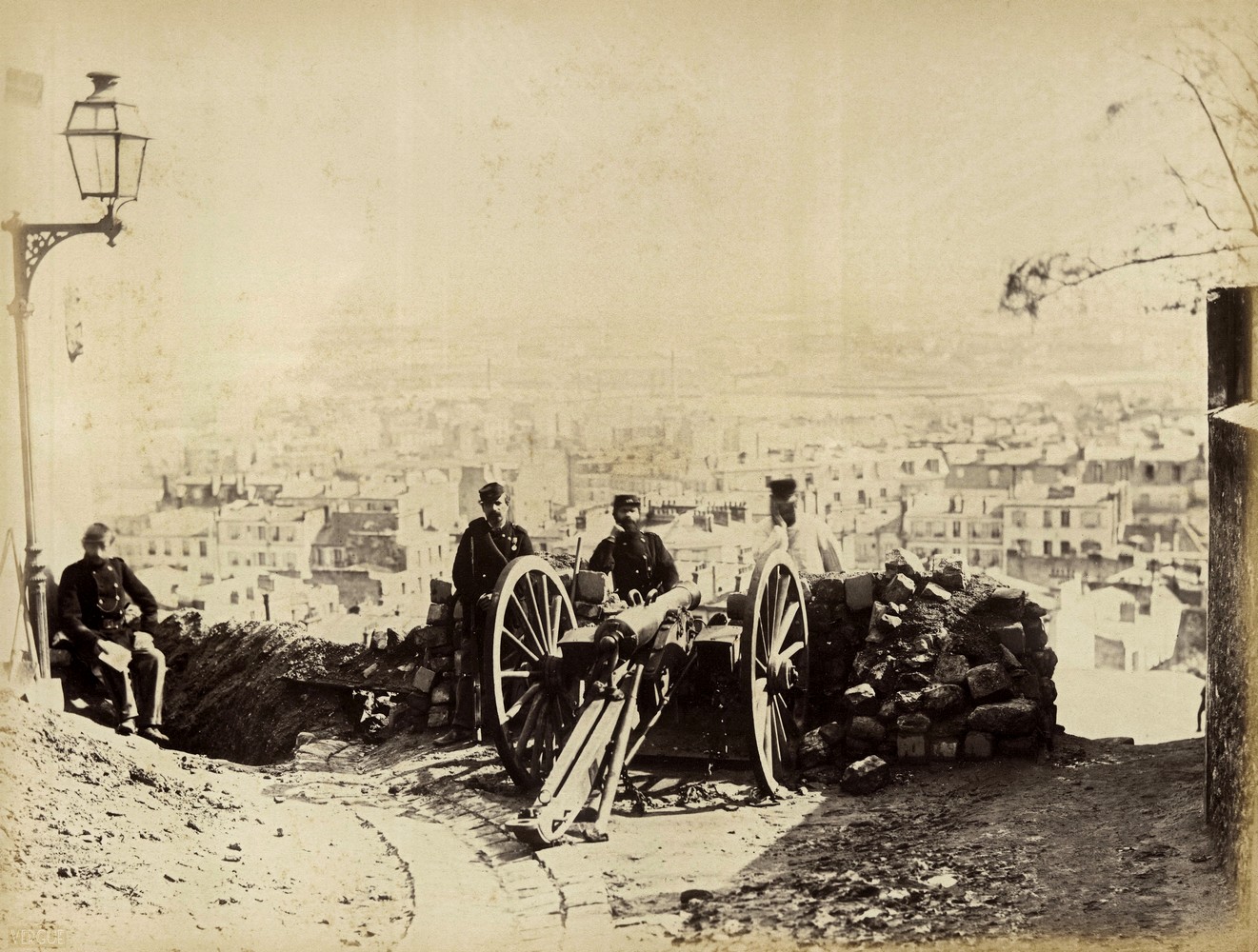 Artilleurs fédérés, rue des Rosiers (Butte Montmartre), Paris XVIIIe. 1871.  Pièce d’artillerie au débouché de l’ancienne rue des Rosiers (Fontenelle), à l’angle de la rue de la Bonne. La rue des Rosiers avait été réunie à la rue de la Fontenelle (et donc renumérotée) par arrêté préfectoral du 2 avril 1868, mais le nouveau nom n’était pas entré dans l’usage en 1871. Photo de Bruno Auguste Braquehais.